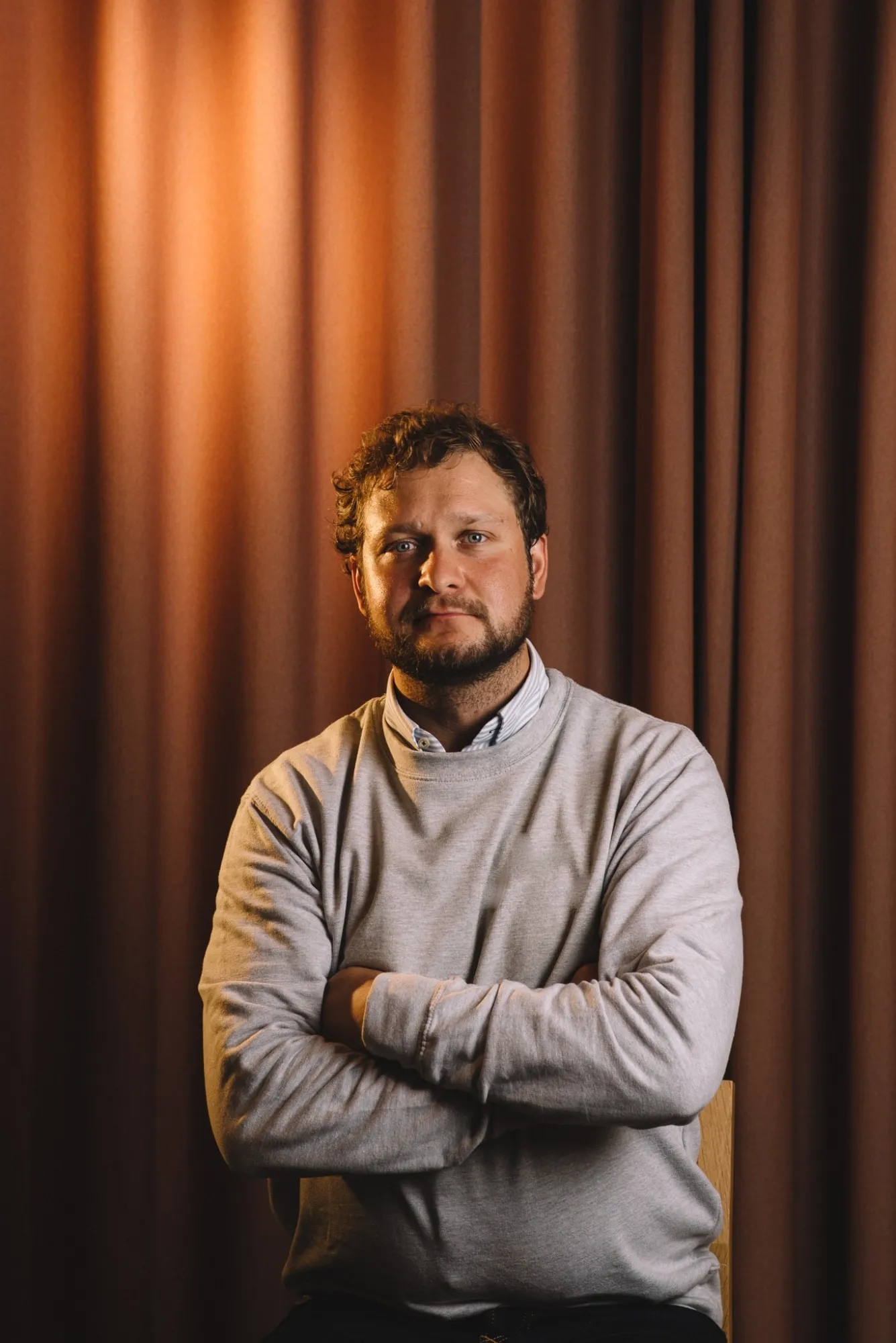 Jyri Taskinen istuu kädet ristissä ja katsoo kameraan
